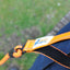 Close-up of an orange and black dog lead with a brand label against a blurred green background